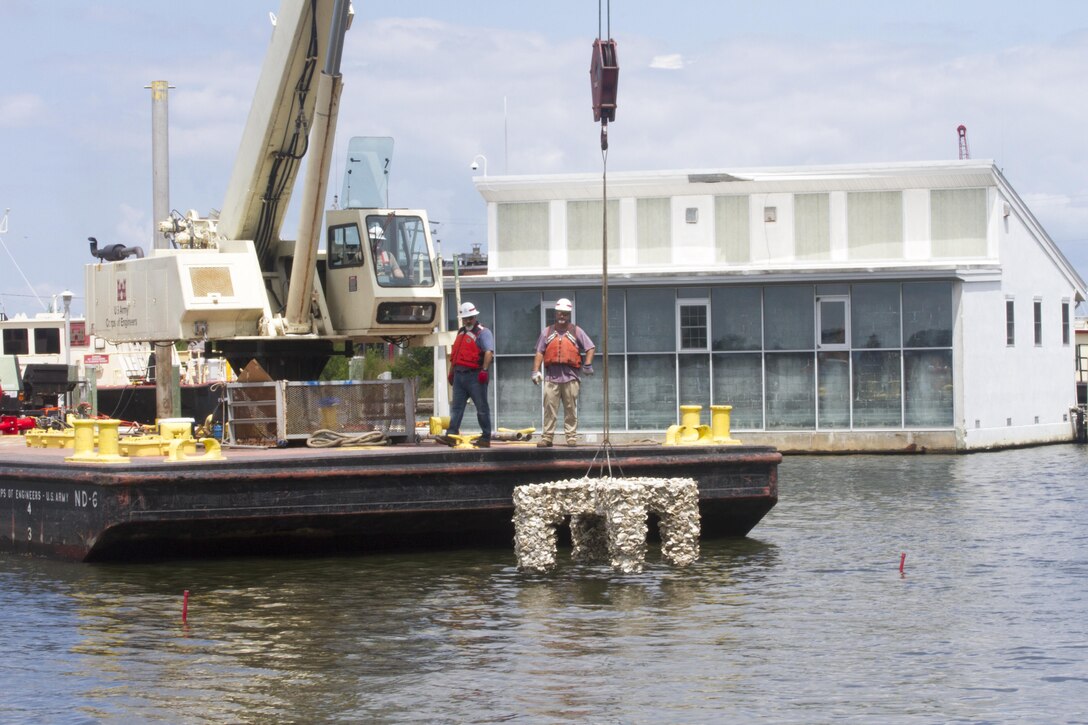 NORFOLK, Va. -- Employees from the Norfolk District use a crane barge to lower an oyster cross into the Elizabeth River at the district's headquarters building near downtown Norfolk on July 26, 2017. Three crosses were placed in the river and will serve as new habitat for oysters. (U.S. Army photo/Patrick Bloodgood)  