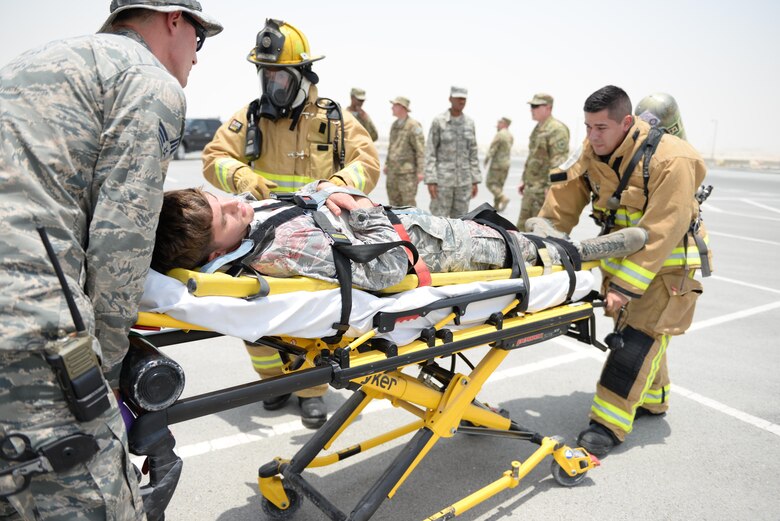 U.S. Air Force Senior Airman Gabriel Weinberg, left, medical technician assigned to the 379th Expeditionary Medical Squadron assists Staff Sgt. Samuel Rochin, firefighter, assigned to the 379th Expeditionary Engineering Squadron in loading a simulated casualty into the back of an ambulance during an emergency response exercise at Al Udeid Air Base, Qatar, July 26, 2017. The exercise was designed to test and demonstrate emergency response capabilities available at Al Udeid Air Base. (U.S. Air National Guard photo by Tech. Sgt. Bradly A. Schneider/Released)