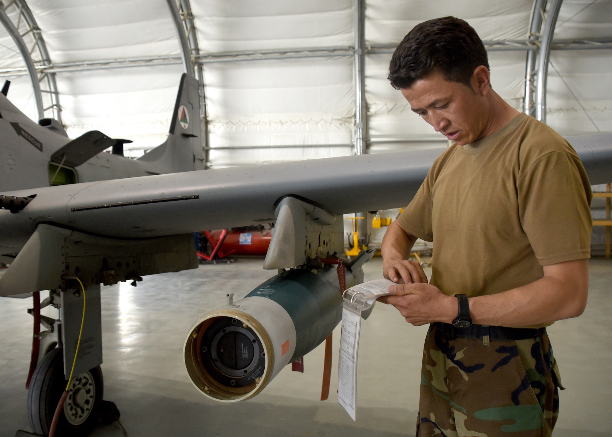 An Afghan Air Force A-29 Super Tucano maintainer reviews technical order instructions before downloading two GBU-12s (Guided Bomb Unit) at Kabul Air Wing, Afghanistan, July 26, 2017. Recently, AAF A-29 maintenance leadership requested to take full responsibility for flight line maintenance operations from Train, Advise, Assist Command-Air advisors and contract maintenance. This initiative by the maintainers is another step closer to the AAF becoming a professional, capable and sustainable force. (U.S. Air Force photo by Tech. Sgt. Veronica Pierce)