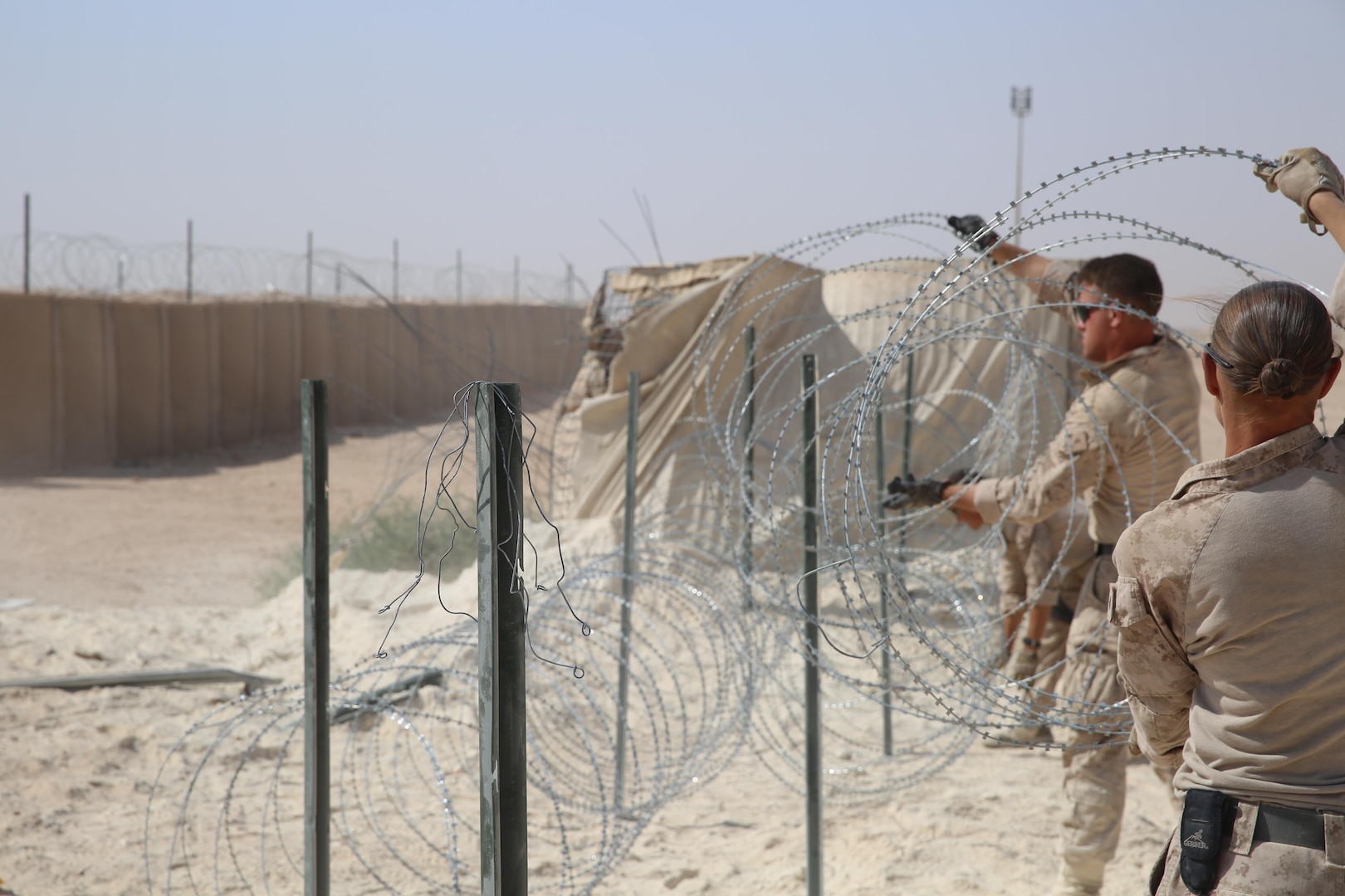 U.S. Marine Corps Cpl. Bridget Bastian and Lance Cpl. Jonathan Fer, both combat engineers attached to Task Force Al Asad with Marine Wing Support Squadron (MWSS) 372 ,Special Purpose Marine Air-Ground Task Force-Crisis Response-Central Command, improve force protection measures by laying concertina wire at Al Asad Air Base, Iraq, July 6, 2017. The Marines of the Engineering Detachment work daily on a variety of engineer tasks in support of the master base plan for Task Force Al Asad. Task Force Al Asad’s mission is to advise and assist  and build partner capacity with the Iraqi Security Forces in Al Anbar province in support of Combined Joint Task Force-Operation Inherent Resolve, the global coalition to defeat ISIS in Iraq and Syria. (U.S. Marine Corps photo by 1st Lt. Dave Williams)