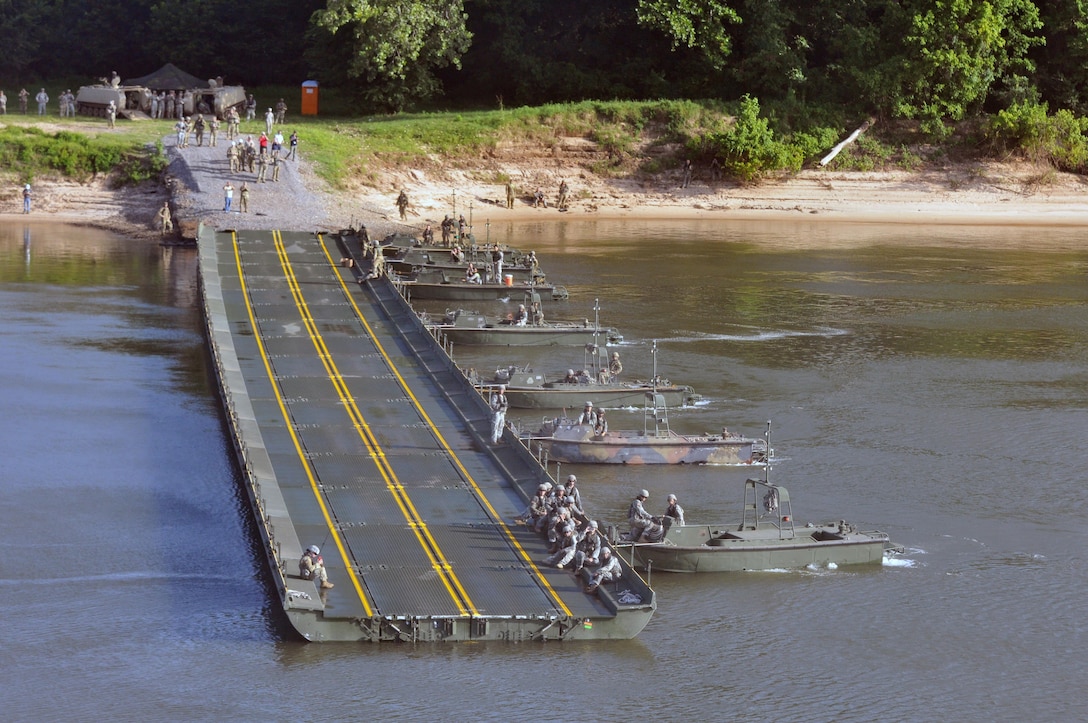 MKII Bridge Erection Boats position against the current Improved Ribbon Bridge (IRB) Bay Sections across the  Arkansas River during River Assault 2017 on Fort Chaffee Manuever Training Center, July 26, 2017. The estimated 300-meter IRB across the river was the culminating event of River Assault. The two M113 Armored Personnel Carriers on the shore were the first two vehicles to drive on the completed bridge. Operation River Assault is one of the key training events that demonstrates that America’s Army Reserve is the most capable, combat ready, and lethal Federal Reserve Force in the history of the nation. (U.S. Army Reserve Photo by Sgt. 1st Class Clinton Wood)