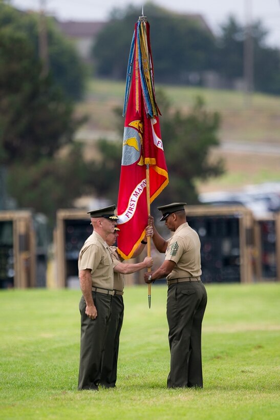 CAMP PENDLETON, CALIF. U.S. Marine Sgt. Maj. Lonnie N. Travis, 1st Marine Logistics Group sergeant major, receives the unit colors from the on-coming commanding general, Brig. Gen. Steven D. Sklenka during the a change of command ceremony at Camp Pendleton July 28, 2017. Approximately 8,000 Marines and Sailors serve numerous occupational specialties within 1st MLG, encompassing six functions of logistics: supply, maintenance, transportation, general engineering, health services, and command services. (U.S. Marine Corps Photo by Sgt. Rodion Zabolotniy)