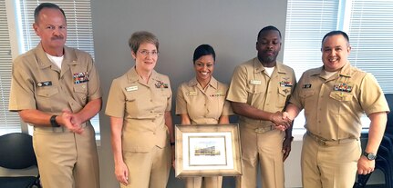 (From left) Capt. Robert Fry, Bureau of Medicine and Surgery; Rear Adm. Rebecca McCormick-Boyle, Navy Medicine Education, Training and Logistics Command commander; Cmdr. Faria Belmares, NMETLC Academics; Senior Chief Damario Payton, NMETLC Academics; and Cmdr. Thomas Sather, BUMED, pose with a framed photo of BUMED Headquarters presented to Belmares and Payton in recognition of their work supporting Navy Medicine education and training. BUMED leaders joined NMETLC and their subordinate commands in attendance at a strategic planning offsite in San Antonio. 