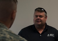 Earl Edwards, American Military University education coordinator, speaks to an Airman at the education fair at Minot Air Force Base, N.D., July 26, 2017. Many universities offer courses for Airmen to complete their Community College of the Air Force degree. (U.S. Air Force photo by Airman 1st Class Alyssa M. Akers)
