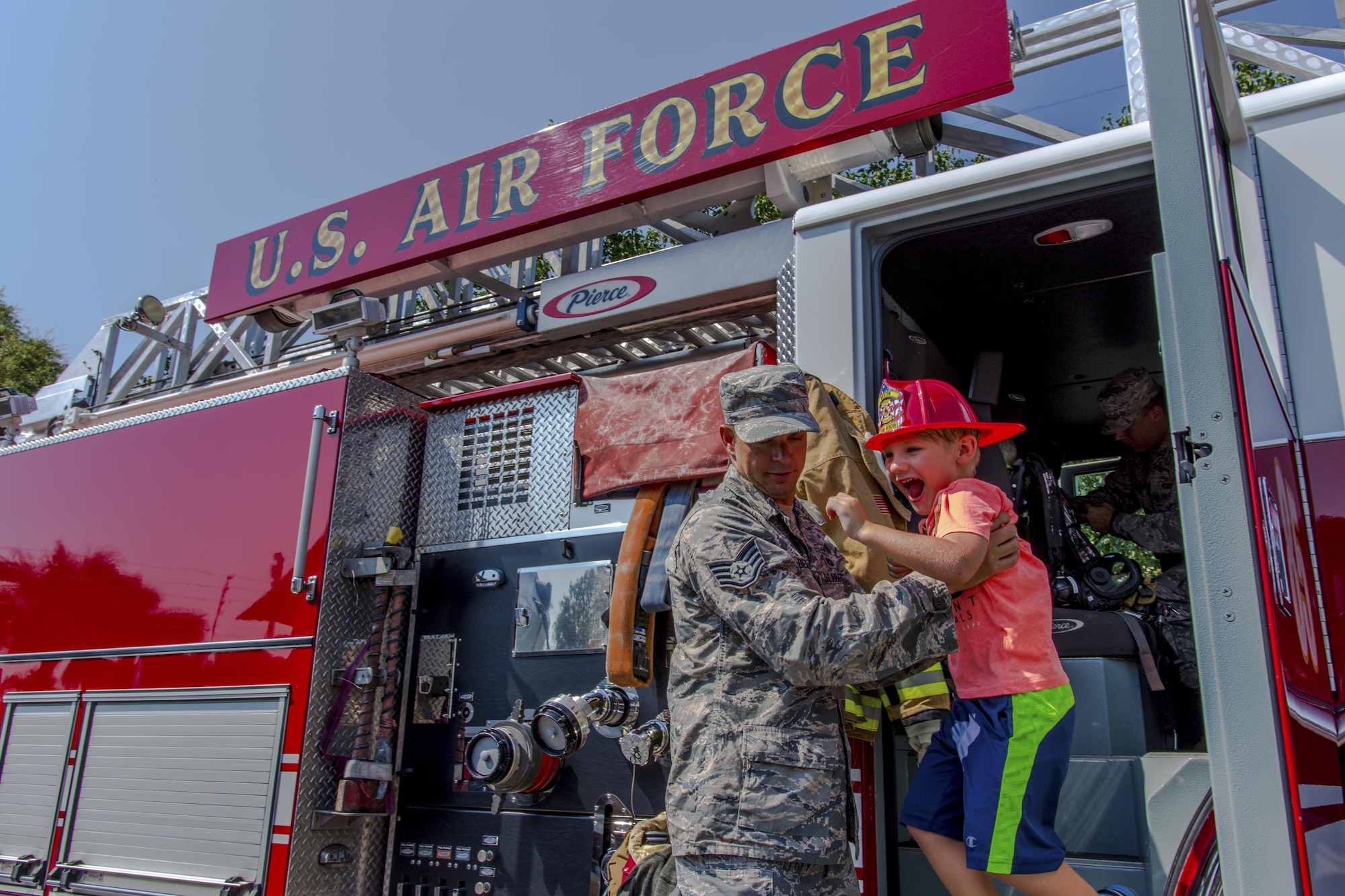 Staff Sgt. Nick Behr, 445th Airlift Wing crew chief, helps a young boy down from a fire engine during Big Truck Day, July 28, Destin, Fla. A 96th Civil Engineer Group fire engine was on display and firefighters educated the public on fire safety. Fire, construction, garbage and utility trucks were on display for kids to see up close at the city’s annual event. (U.S. Air Force photo/Kristin Stewart)