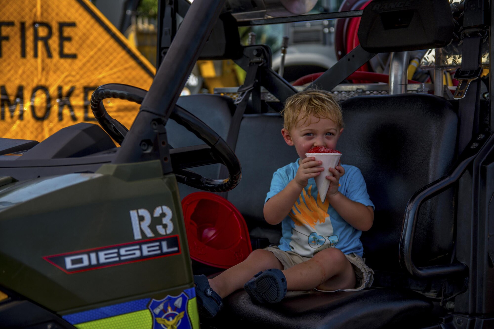 A young boy eats a snow cone while sitting in a Jackson Guard water ranger vehicle during Big Truck Day, July 28, Destin, Fla. Jackson Guard displayed their forestry vehicles and educated event goers about their use during prescribed burns. Fire, construction, garbage and utility trucks were on display for kids to see up close during the city’s annual event. (U.S. Air Force photo/Kristin Stewart)