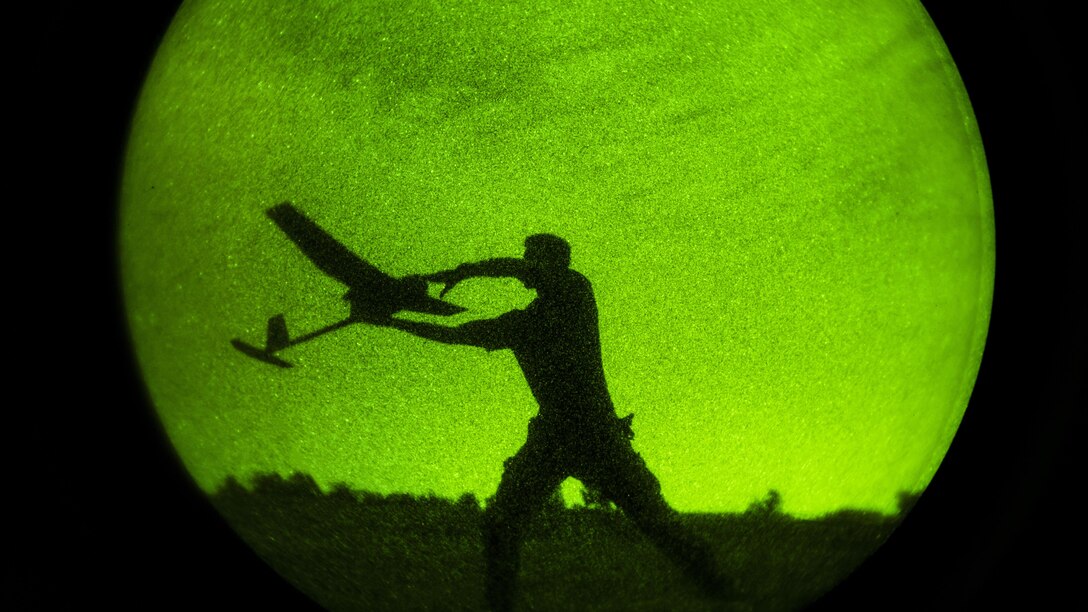As seen through a night-vision device, Army Spc. Derek Opthof winds up to throw an RQ-11 Raven unmanned aerial vehicle during exercise Panther Storm at Fort Bragg, N.C., July 27, 2017. The exercise tests the division's ability to rapidly deploy its global response force anywhere in the world within a short notice. Air Force photo by Staff Sgt. Andrew Lee