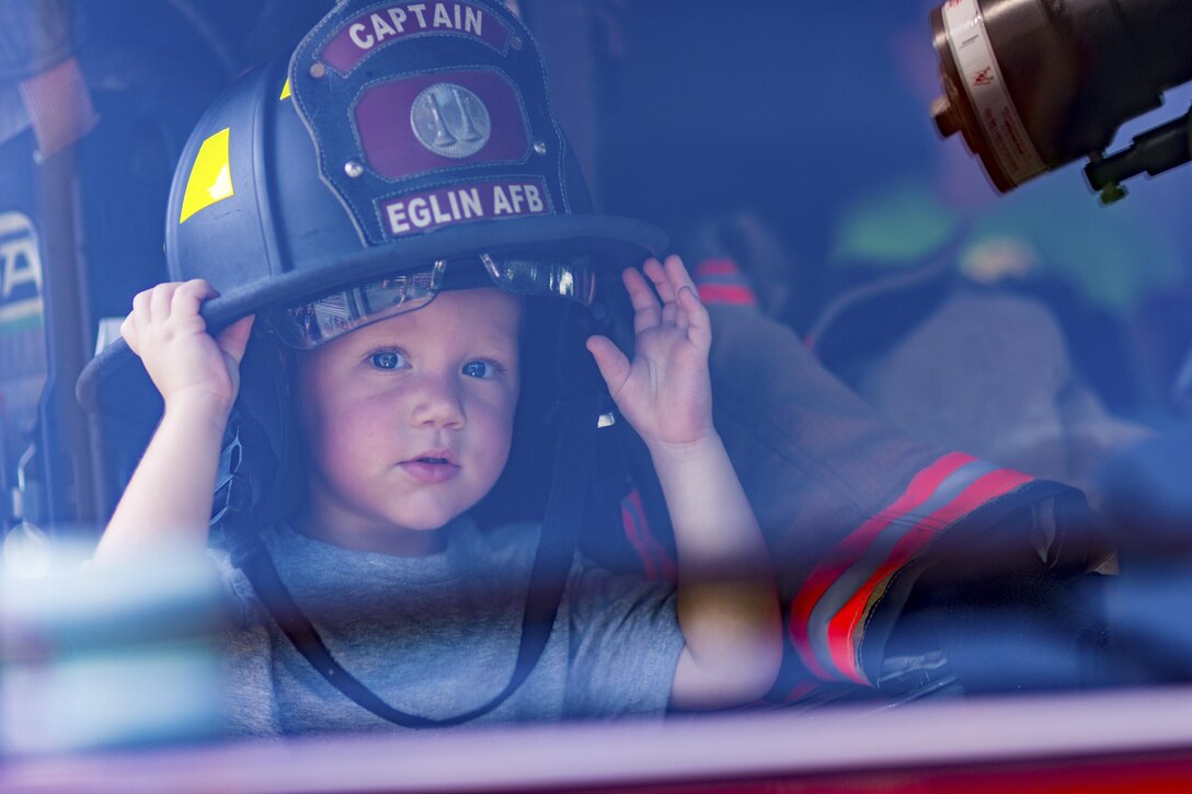A little boy tries on a fire captain’s helmet. A 96th Civil Engineer Group fire engine was on display and firefighters educated the public about fire safety on Big Truck Day, July 28, Destin, Fla. Fire, construction, garbage and utility trucks were on display for kids to see up close during the city’s annual event. (U.S. Air Force photo/Kristin Stewart)
