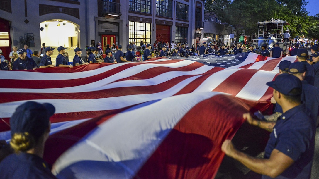 Coast Guardsmen and Coast Guard Auxiliary members carry a long U.S. flag during the Seafair Torchlight Parade in Seattle, July 29, 2017. The parade remains one of the longest running annual events in the Seattle area, dating back to the 1950s. Coast Guard photo by Petty Officer 1st Class Ayla Kelley.