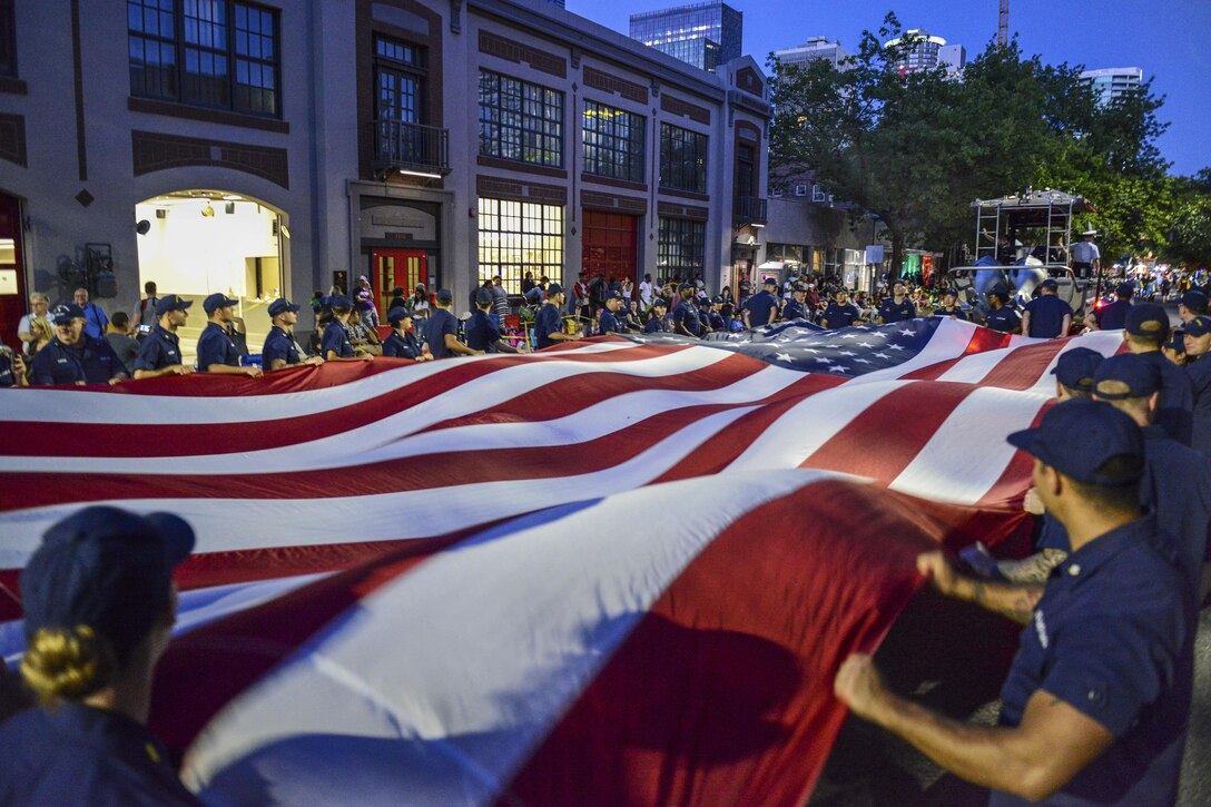 Coast Guardsmen and Coast Guard Auxiliary members carry a long U.S. flag during the Seafair Torchlight Parade in Seattle, July 29, 2017. The parade remains one of the longest running annual events in the Seattle area, dating back to the 1950s. Coast Guard photo by Petty Officer 1st Class Ayla Kelley.