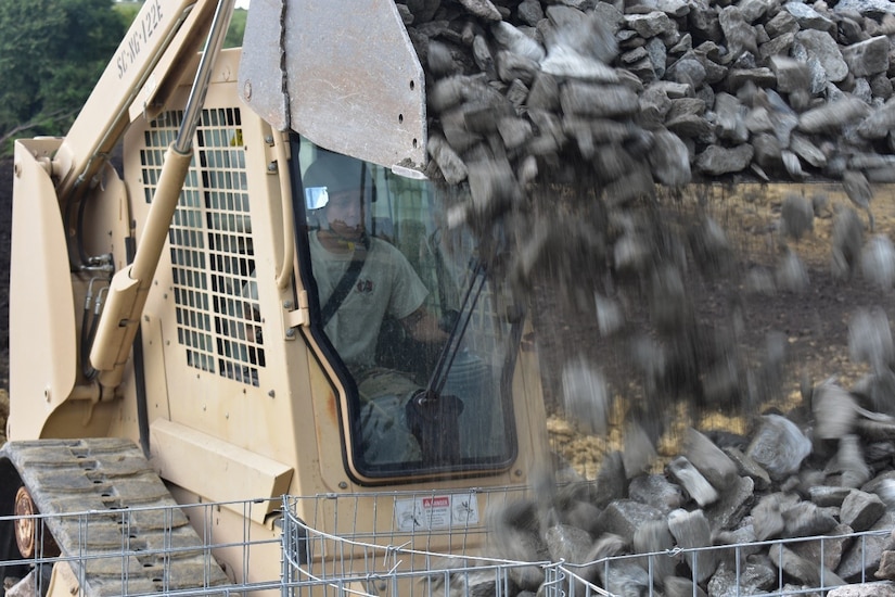 Spc. Alvin Stevens pours rock into Gabion baskets from his Skidsteer loader.  These Gabion baskets will support moving targetry at a tank range at Joint National Training Center, Cincu, Romania. Spc. Stevens is a South Carolina Army National Guard Soldier with the 1223rd Engineer Company, 178th Engineer Battalion, serving in Romania as part of Resolute Castle 17, an operation which builds relationships with the NATO alliance and enhances its capacity for joint training and response to threats within the region.