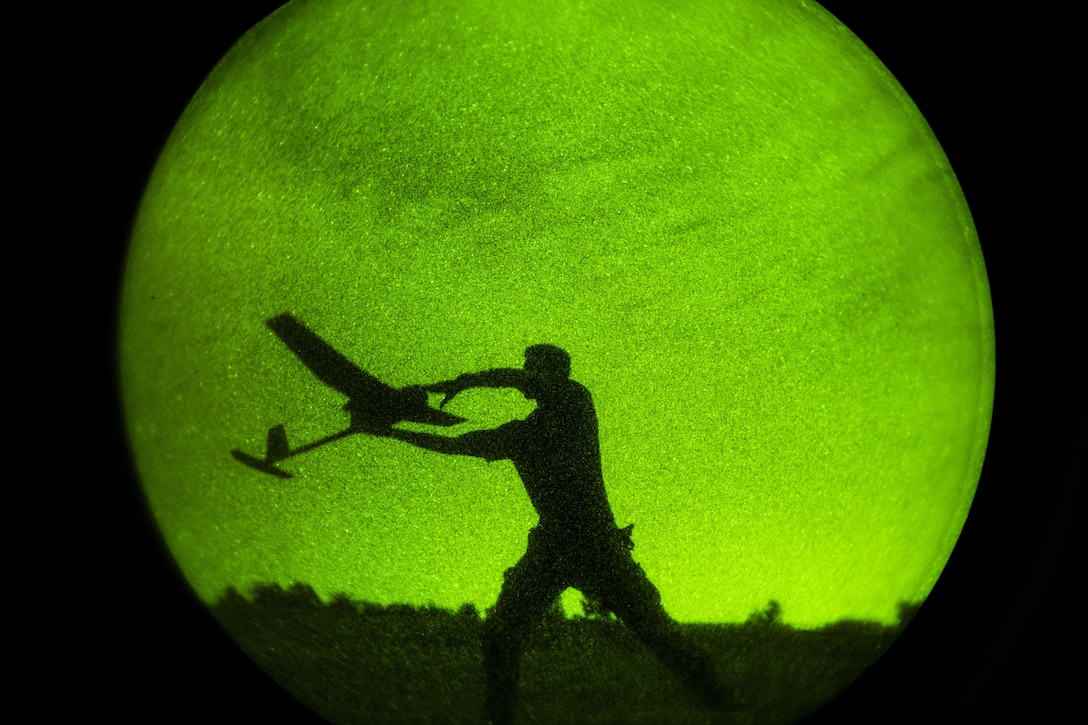 As seen through a night-vision device, Army Spc. Derek Opthof winds up to throw an RQ-11 Raven unmanned aerial vehicle during exercise Panther Storm at Fort Bragg, N.C., July 27, 2017. The exercise tests the division's ability to rapidly deploy its global response force anywhere in the world within a short notice. Air Force photo by Staff Sgt. Andrew Lee