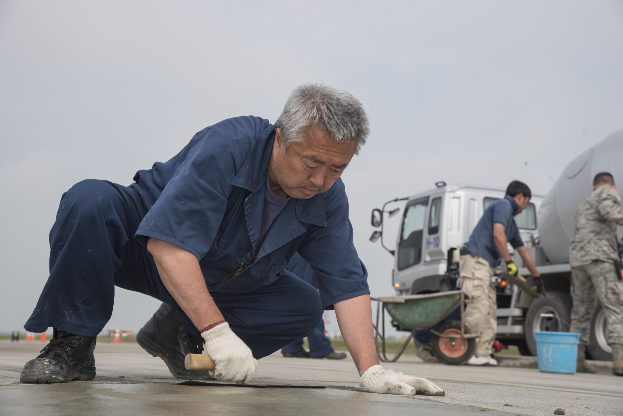 Youichi Yamada, a Japanese contractor, uses a trowel to put finishing touches on newly laid concrete at Misawa Air Base, Japan, May 23, 2017. AFter concrete is laid down, it is smoothed out with a trowel, which pushes heavier rocks down and provides a clean, smooth surface. (U.S. Air Force photo by Airman 1st Class Sadie Colbert)