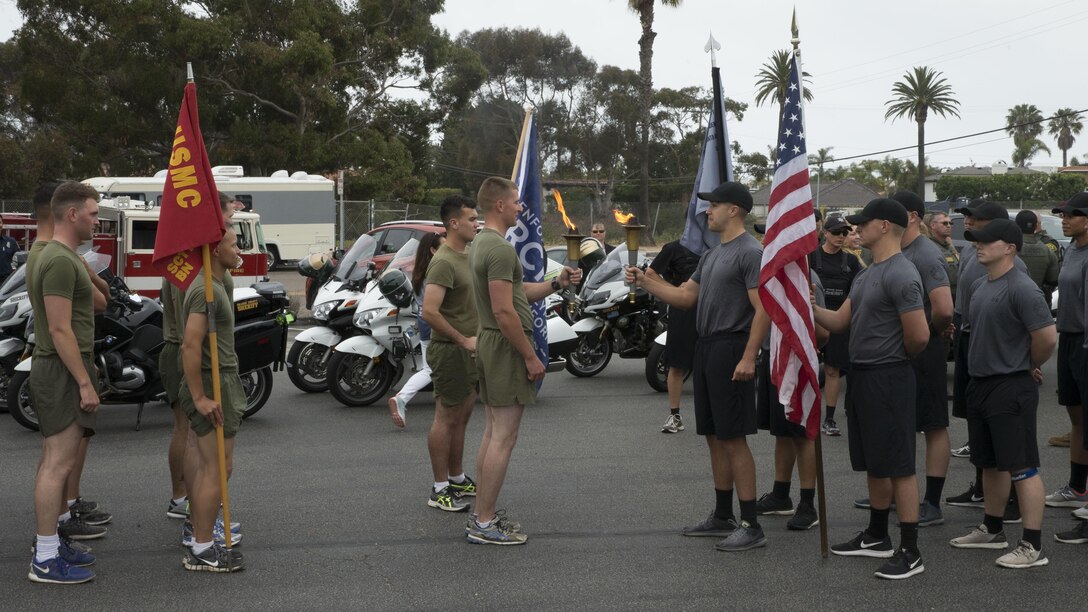 U.S. Marines with Security and Emergency  Services Battalion, Marine Corps Base Camp Pendleton, Marine Corps Installations–West, hands off the torch to Orange County Sheriff Department Special Olympics torch from runners of the Oceanside Police Department at San Clemente, Calif., May 31st, 2017. More than 30 Marines from the SES and  the installation Provost Marshal Office participated in the 2017 Law Enforcement Torch Run in support of the Special Olympics. The Marines received the torch from runners with the Oceanside Police Department at the Camp Pendleton Main Gate, Calif., May 31st, 2017. SES Bn. Marines then relayed the torch and ran it 17 miles to San Clemente.