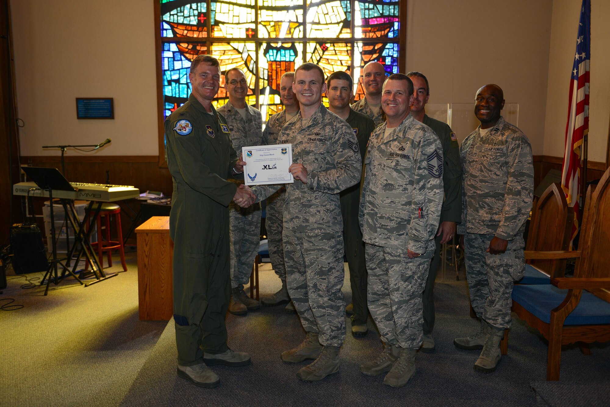 U.S. Air Force Staff Sgt. Jason Black, 47th Flying Training Wing Chapel plans and programs NCO in charge, (center), accepts the “XLer of the Week” award from Col. Thomas Shank, 47th Flying Training Wing commander (left), and Chief Master Sgt. Allen Turk, 47th Operations Support Squadron superintendent (right), on Laughlin Air Force Base, Texas, May 25, 2017. The XLer is a weekly award chosen by wing leadership and is presented to those who consistently make outstanding contributions to their unit and installation. (U.S. Air Force photo/Airman 1st Class Benjamin N. Valmoja)