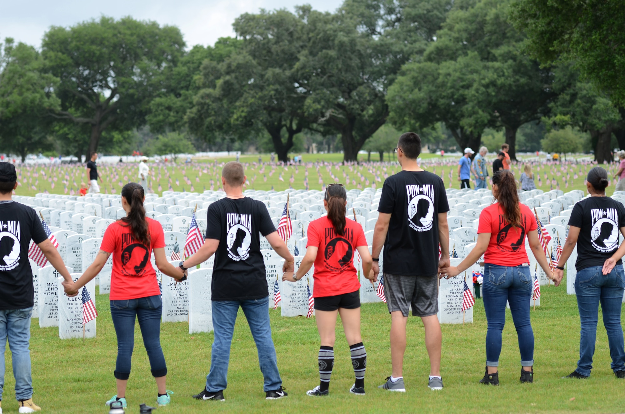 Keesler Airmen stand hand-in-hand at Biloxi National Cemetery in recognition of Memorial Day, May 27, 2017, in Biloxi, Miss. Local veterans, family members and Keesler AFB personnel placed U.S. flags to honor and remember the lives of fallen heroes of the U.S. military. (U.S. Air Force photo by Andrew Whitman)