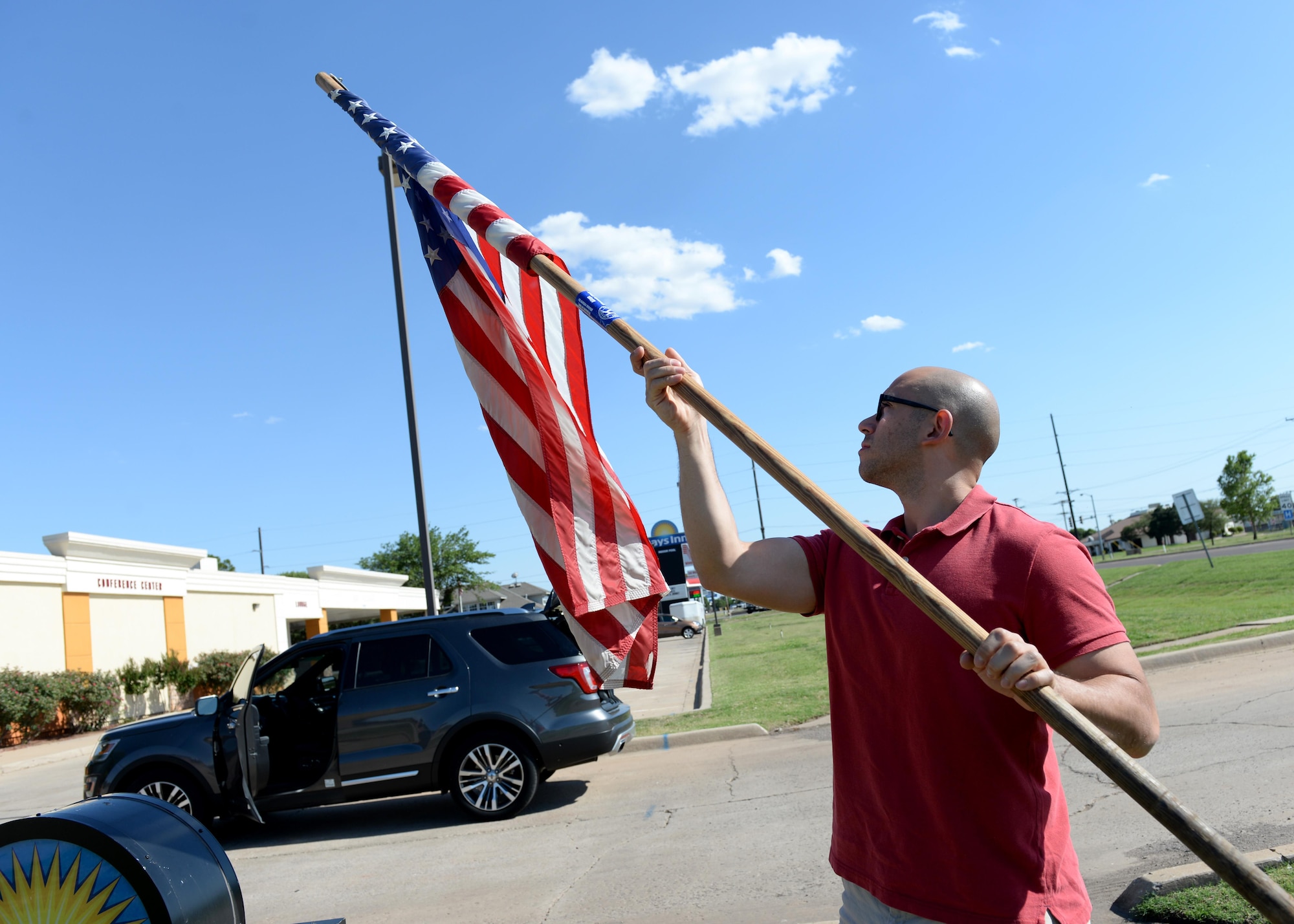 U.S. Air Force Staff Sgt. Gerson Medina, 97th Operations Support Squadron watch supervisor, retrieves a flag from the local community, May 29, 2017, at Altus, Oklahoma. Members of the 97th OSS took time during the Memorial Day holiday to place flags around the community showing support for community, and base relations. The 97th OSS preforms this service six times a year for federal holidays that relate to the military. (U.S. Air Force Photo by Airman 1st Class Jackson N. Haddon/Released).