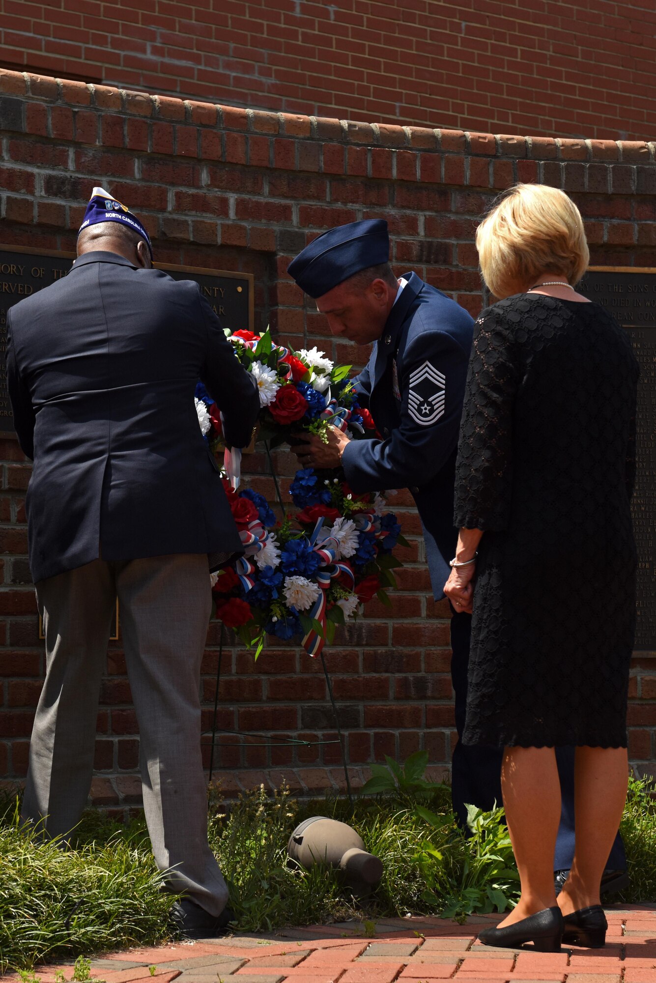 Sylvania Wilkerson (left), the Military Order of the Purple Heart commander, Chief Master Sgt. Eugene Elking, acting 4th Fighter Wing command chief (center), and Brenda Albritton (right), U.S. Air Force Gold Star wife, place a commemorative wreath, May 29, 2017, at the Wayne County Veterans Memorial in Goldsboro, North Carolina. Veterans in Wayne County gathered to hold a moment of silence to honor the fallen. (U.S. Air Force photo by Senior Airman Ashley Maldonado-Suarez)