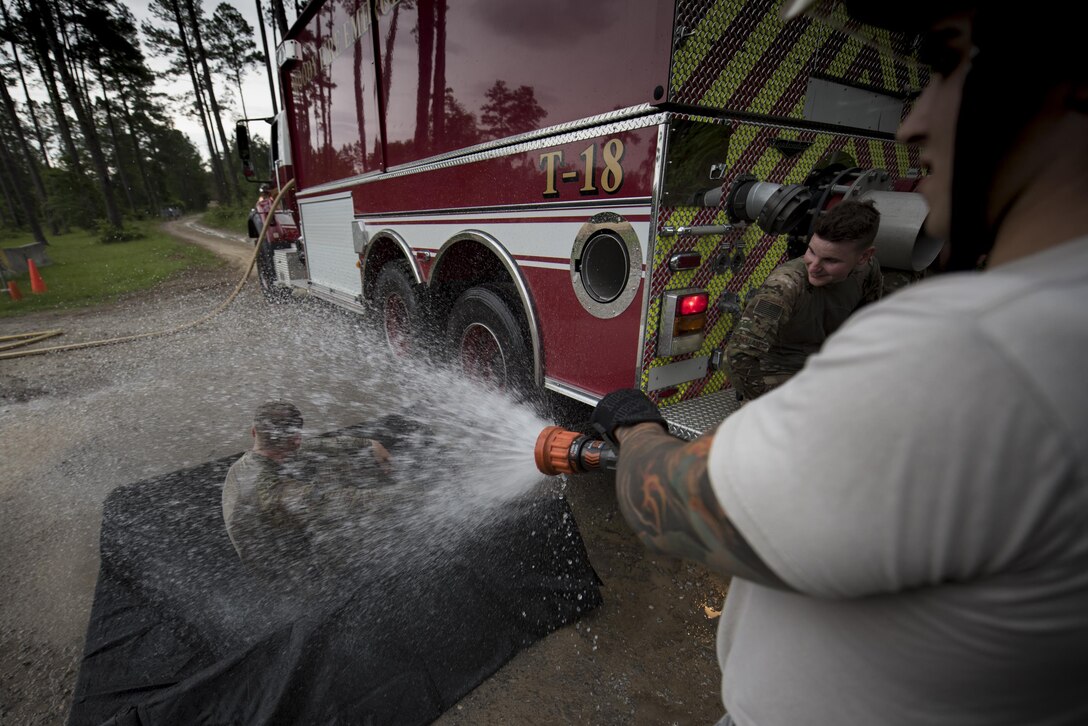 Senior Airman Frank Boniello, 23d Civil Engineer Squadron firefighter performs an initial decontamination of Senior Airman Jonah Phillips, 822d Base Defense Squadron fireteam member during a simulated explosives and hazardous material scenario, May 24, 2017, at Moody Air Force Base, Ga. The exercise simulated initial responses from first responders who then contacted other appropriate units after assessing the potential threat while also assisting the simulated victims of hazardous materials. (U.S. Air Force photo by Airman 1st Class Daniel Snider)