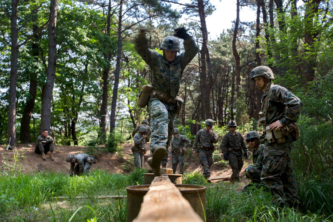 Marines and sailors cross a wooden plank obstacle that's part of the Leadership Reaction Course at Camp Mujuk, South Korea, May 29, 2017. Marine Corps photo by Cpl. David A. Diggs