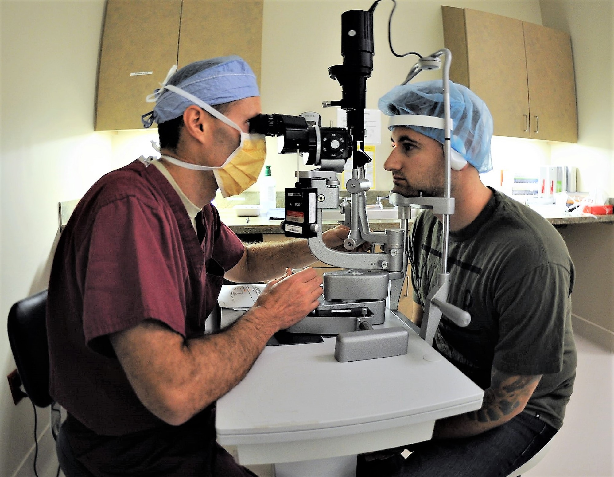 Maj. Williams Gensheimer (left), 779th Medical Group’s Warfighter Eye Center chief, inspects the corneas of Staff Sgt. John Scacca, 633rd Medical Group, Joint Base Langley-Eustis, Va., before performing corneal refractive surgery May 17, 2017 at Joint Base Andrews, Md. PRK, LASIK and other types of laser eye surgery involve using an excimer laser to re-shape the cornea, which allows for light to enter the eye that is properly focused onto the retina for improved vision. (U.S. Air Force photo by Joe Yanik)
