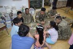 U.S. Soldiers and Korean Augmentees to the United States Army assigned to 35th Air Defense Artillery Brigade, and children from the Pyeongtaek Local Children's Center, play a competitive game of cards at the Pyeongtaek Local Children's Center May 30, 2017 during a community outreach event. 