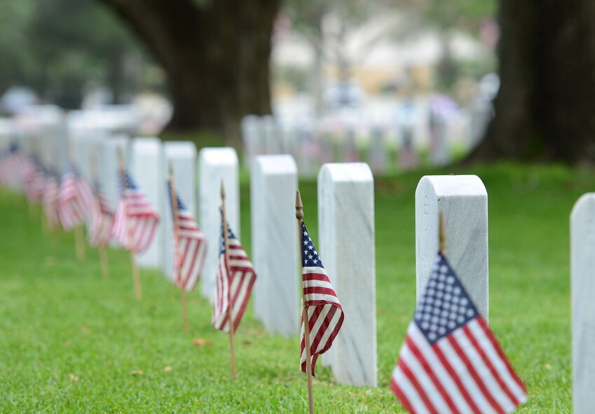 U.S. flags stand in front of tomb stones at Biloxi National Cemetery in recognition of Memorial Day, May 27, 2017, in Biloxi, Miss. Local veterans, family members and Keesler AFB personnel participated in the event to honor and remember the lives of fallen heroes of the U.S. military. (U.S. Air Force photo by Andrew Whitman)