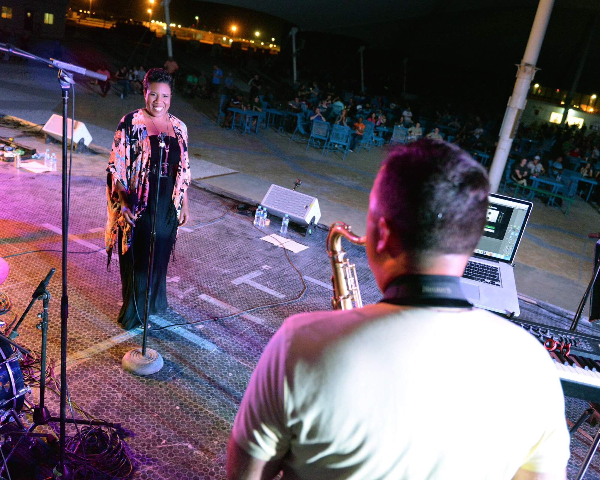 Melinda Doolittle, an accomplished vocalist and top finisher on American Idol, looks on as U.S. Air Force Technical Sgt. Ryan Janus, Air Forces Central Command Band keyboard player and saxophonist, plays a solo on the saxophone during a concert at Al Udeid Air Base, Qatar, May 25, 2017. Doolittle performed for service members deployed overseas, accompanied by the Air Forces Central Command Band. (U.S. Air Force photo by Tech. Sgt. Bradly A. Schneider/Released)