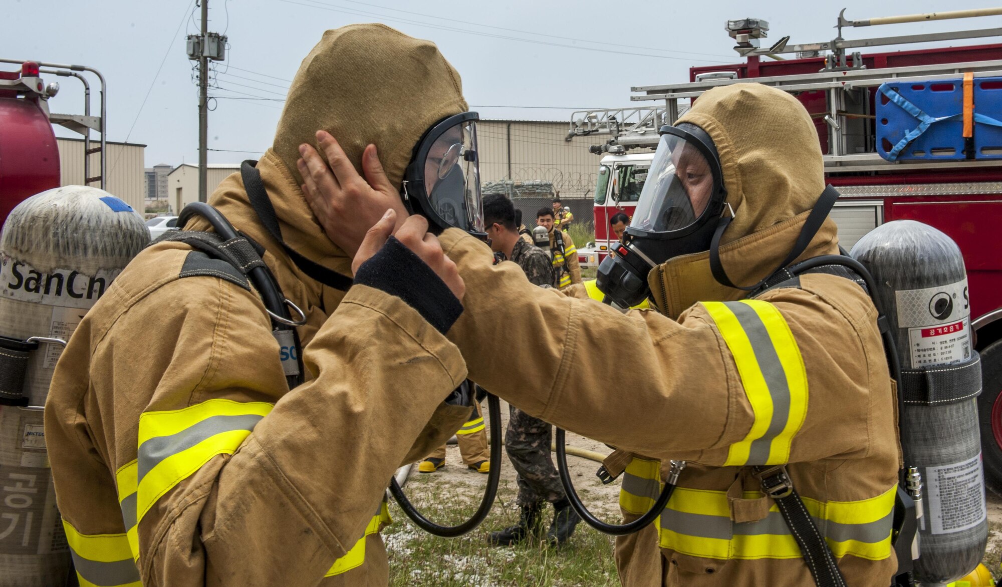 Republic of Korea Air Force firefighters perform buddy checks while donning personal protective gear during a combined fire training exercise at Kunsan Air Base, Republic of Korea, May 23, 2017. The firefighters conducted safety checks to ensure no skin was exposed during the live fire training portion of the exercise. (U.S. Air Force photo by Senior Airman Colville McFee/Released)