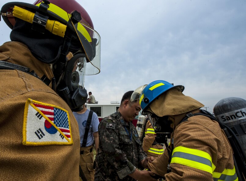 Republic of Korea Air Force firefighters, perform buddy checks while donning personal protective gear during combined live fire training at Kunsan Air Base, Republic of Korea, May 23, 2017. The firefighters conducted safety checks to ensure no skin was exposed during the live fire portion of the training. (U.S. Air Force photo by Senior Airman Colville McFee/Released)