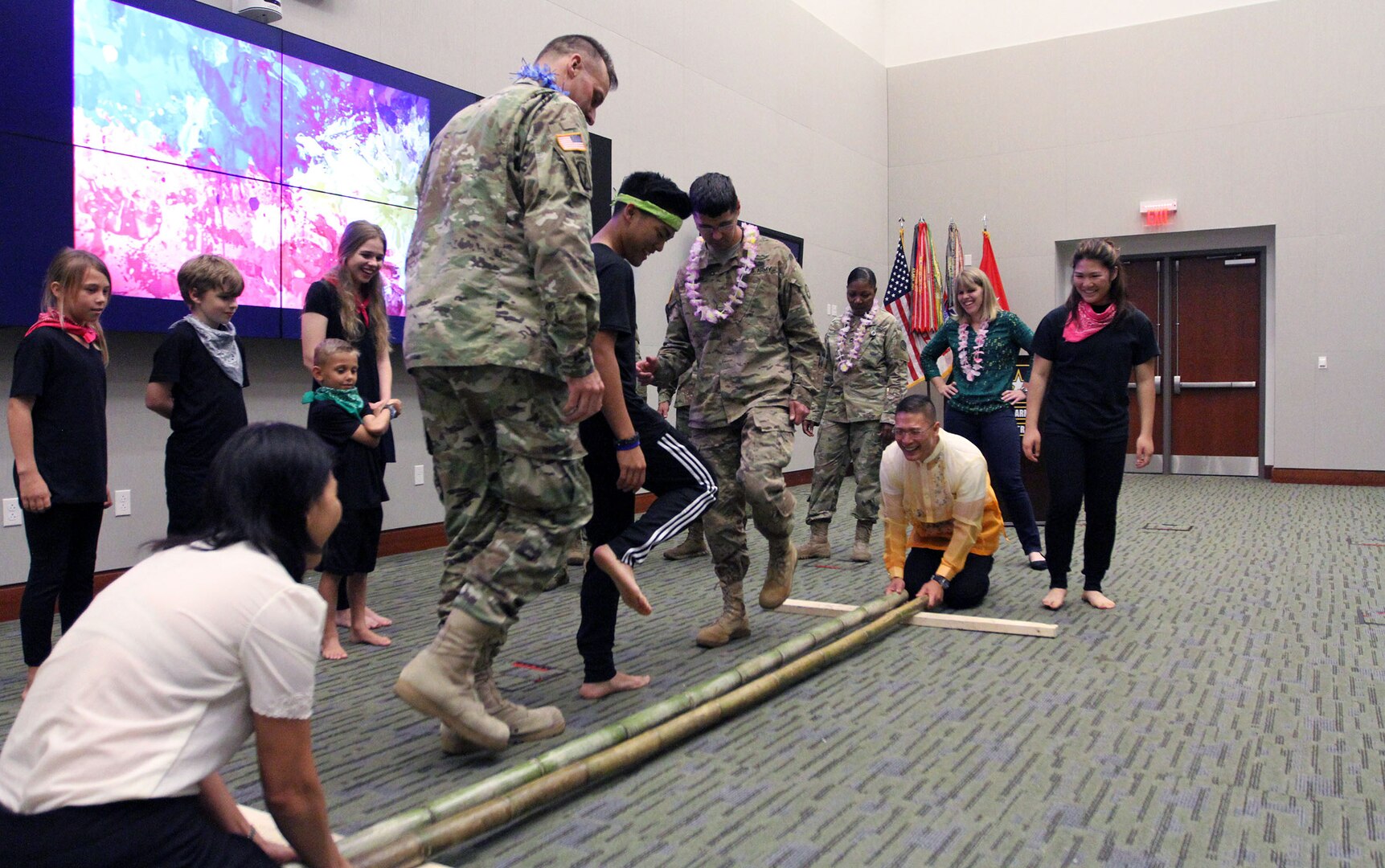 Several U.S. Army Central children teach the Tinikling to USARCENT members, as Col. Roy Banzon, USARCENT inspector general commander, and Marlyn Banzon, Banzon’s wife, hit and tap the bamboo poles in rhythm to the music during USARCENT’s observance for Asian American and Pacific Islander Heritage Month at Patton Hall May 24. (U.S. Army Photo by Sgt. Matthew Kuzara) 