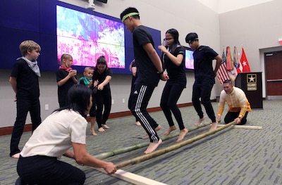 Several U.S. Army Central children perform the Tinikling, as Col. Roy Banzon, USARCENT inspector general commander, and Marlyn Banzon, Banzon’s wife, hit and tap the bamboo poles in rhythm to the music during USARCENT’s observance for Asian American and Pacific Islander Heritage Month at Patton Hall May 24. (U.S. Army Photo by Sgt. Matthew Kuzara) 