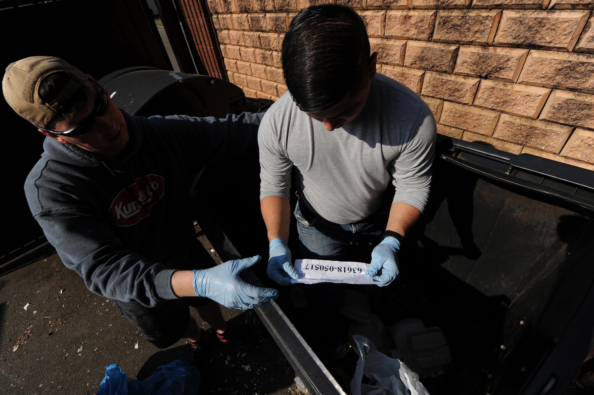 Air Force Tech. Sgt. Calin A. Cronin, 86th Security Forces Squadron police services noncommissioned officer in-charge and Operations Security unit coordinator, left, and Staff Sgt. Brandon Trinidad, 86th SFS police services section assistant, review discarded paperwork in a dumpster on Ramstein Air Base, May 30, 2017. The 86th AW OPSEC program team and unit coordinators conducted a risk assessment for potentially improperly disposed critical information in order to further educate units about protecting sensitive information. (U.S. Air Force photo by Staff Sgt. Nesha Humes)