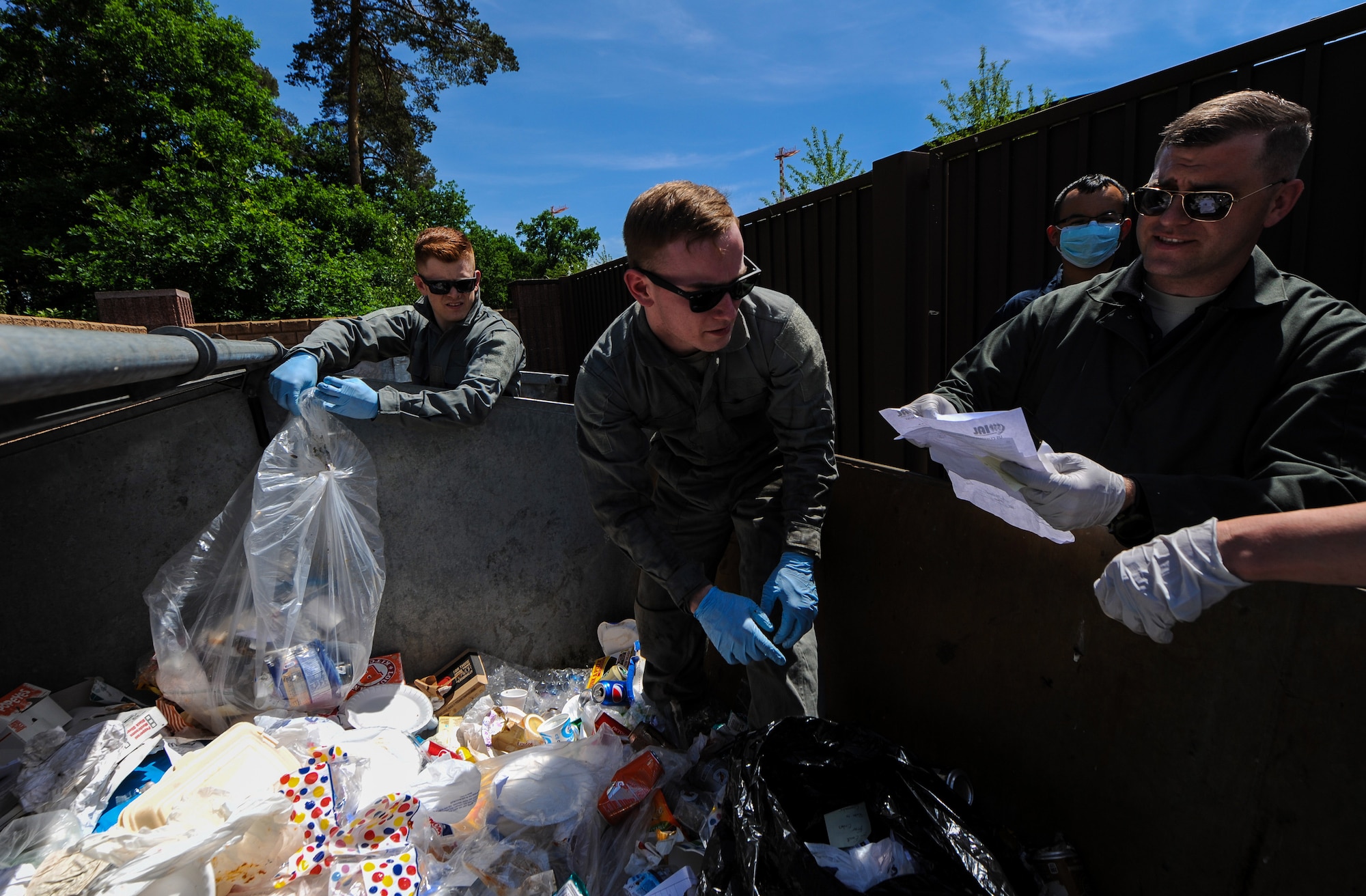 Airmen from the 86th Airlift Wing search and review discarded paperwork in a dumpster for potential improperly disposed critical information during a risk assessment on Ramstein Air Base, May 31, 2017. The 86th AW Operations Security program team and unit coordinators conducted a risk assessment for improperly disposed critical information in order to further educate units on protecting sensitive information. (U.S. Air Force photo by Staff Sgt. Nesha Humes)