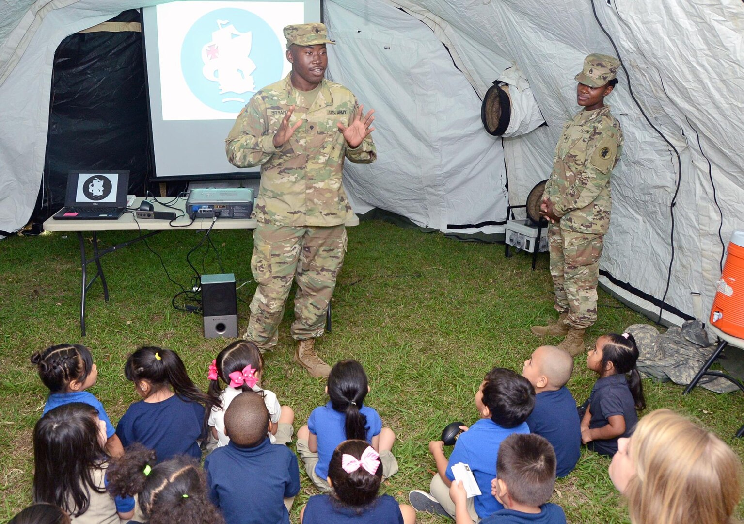 Spc. David Bryant (left) and Staff Sgt. Ashley Moore (right), Headquarters and Headquarters Battalion, U.S. Army South at Joint Base San Antonio-Fort Sam Houston, answer questions from students at Booker T. Washington Elementary School, during the school’s career day May 26.  The school and unit are partnered through the Adopt-a-School program. Units on JBSA-Fort Sam Houston are partnered with schools with the Northeast Independent School District, the San Antonio Independent School District and the Fort Sam Houston Independent School District. Throughout the year, Soldiers partner with their designated school and provide mentorship to students as well as assist with career days, field trips and many other activities.