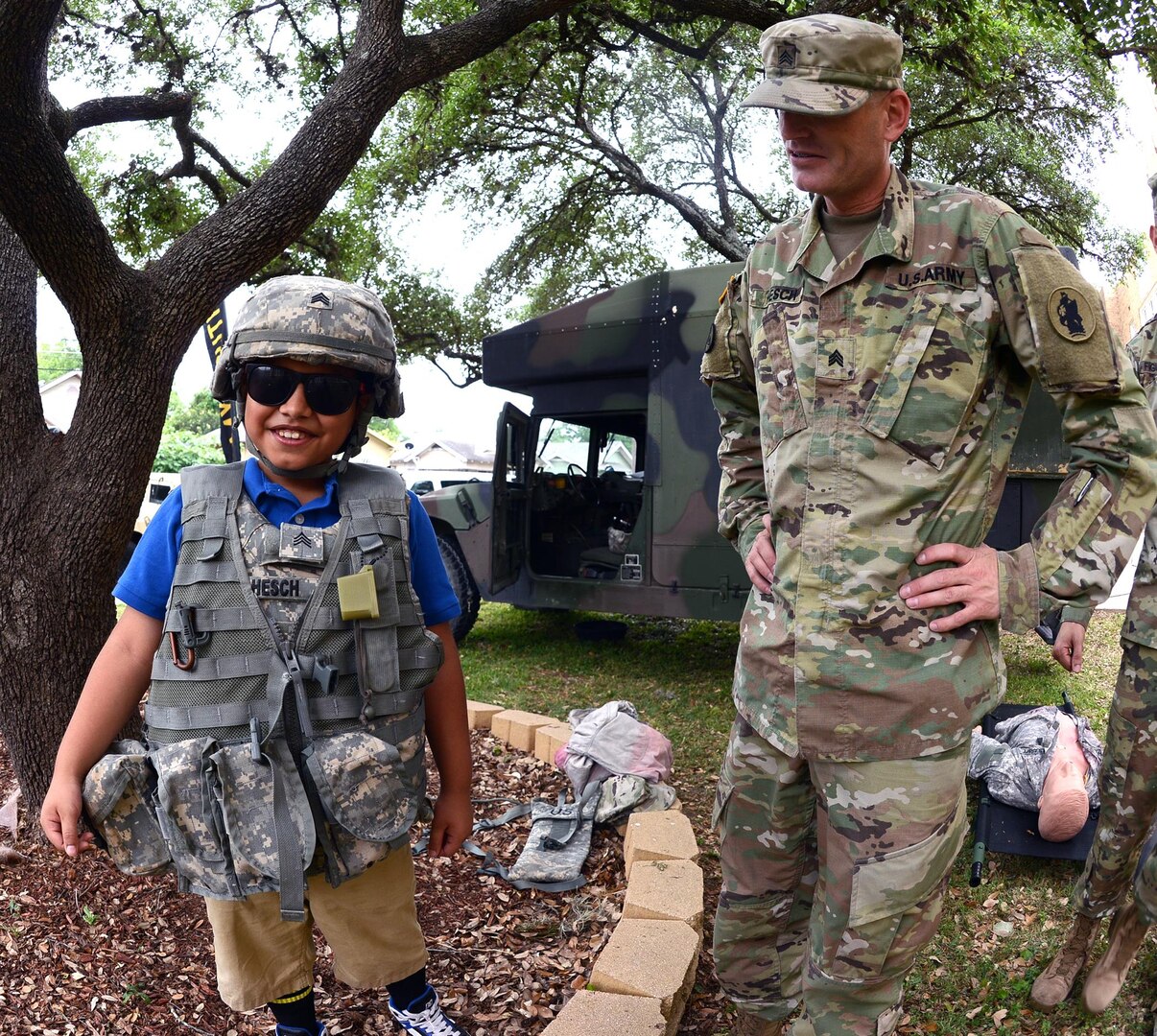 Sgt. Drew Hesch, Headquarters and Headquarters Battalion, U.S. Army South, looks at a student as he wears Hesch’s body armor, during Booker T. Washington Elementary School’s Career Day May 26.  Hesch demonstrated to the student the proper way to wear the armor. 
