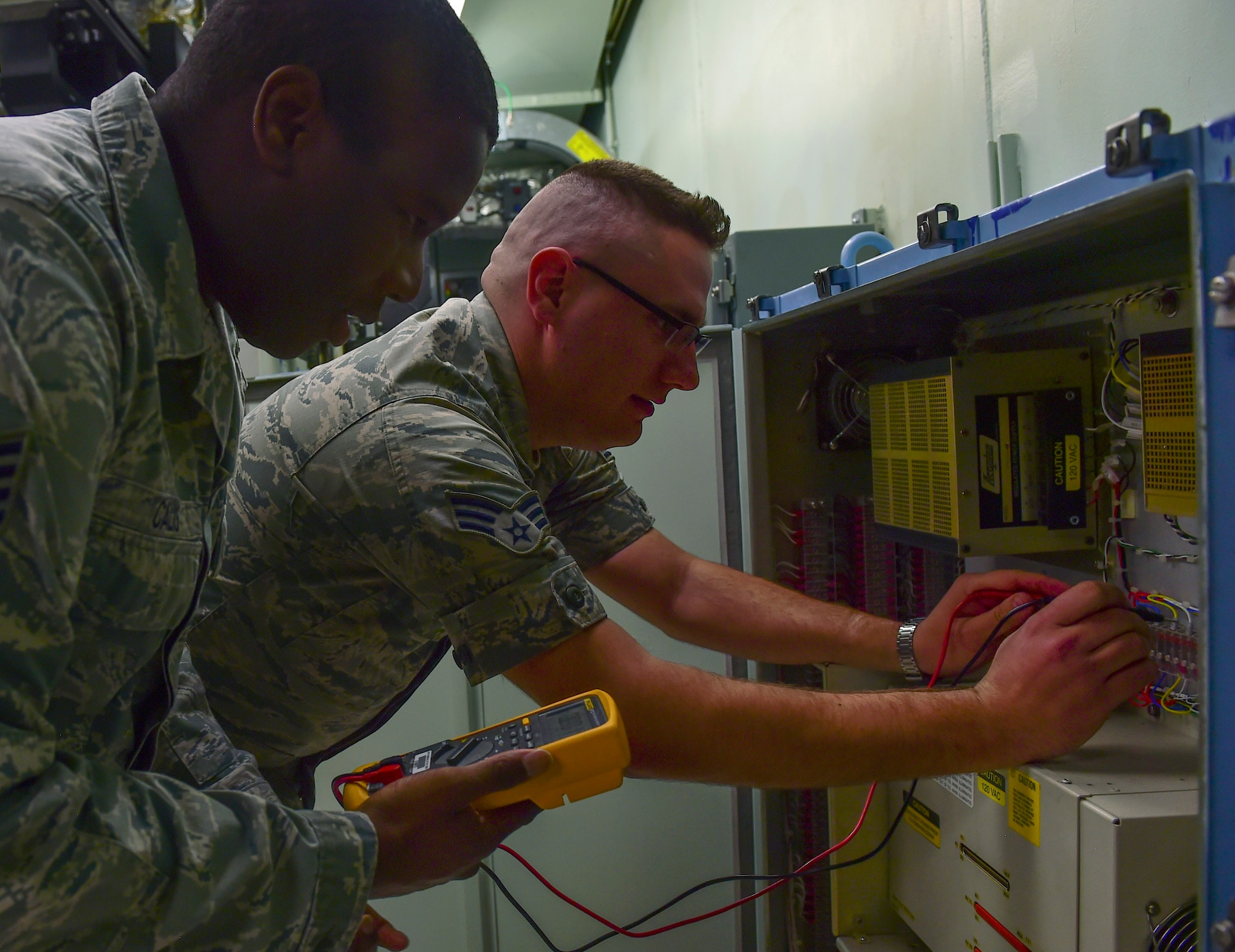 Staff Sgt. Dexter Calis, 460th Space Communications Squadron satellite communication supervisor and Senior Airman James Ramroth, 460th SCS SATCOM technician, perform multi-meter testing March 15, 2017, on Buckley Air Force Base, Colo. SATCOM ensures the flow data and connection between satellites and their end-users. (U.S. Air Force photo by Airman Jacob Deatherage/Released)