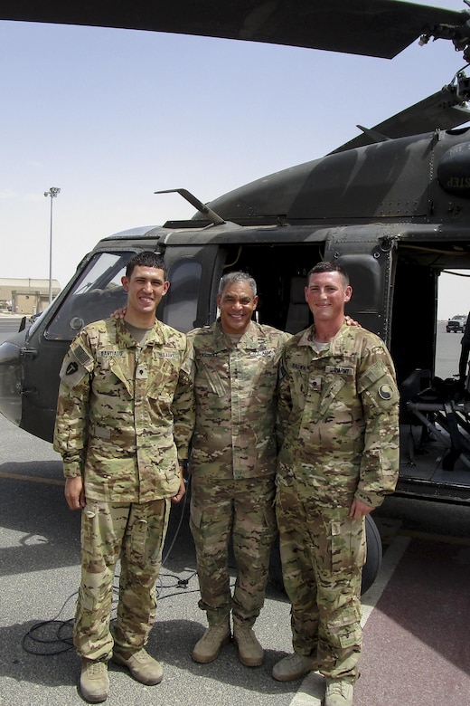 Lt. Gen. Michael Garrett, the commanding general of U.S. Army Central, poses with (left) Spc. Jesus Santiago, a UH-60 Blackhawk helicopter crew chief, for A Company, 2nd General Support Aviation Battalion, 149th Aviation Regiment, and Spc. Benjamin Baldwin, a UH-60 Blackhawk helicopter crew chief, for A Company, 2nd General Support Aviation Battalion, 149th Aviation Regiment, after an impromptu combat patch ceremony on the helicopter landing pad, on Ali Al Salem Air Base, May 20. Garrett surprised the crew chiefs with the impromptu stop and shared his story of how he received his first combat patch.  (U.S. Army photo by Lt. Col. Derek Johnson, USARCENT)