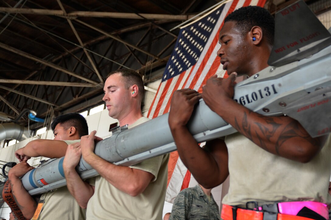 U.S. Air Force Staff Sgt. Michael Finney, 20th Aircraft Maintenance Squadron (AMXS) weapons load crew chief, center, and Senior Airmen Johan Briones, left, and Avery Kemp, right, 20th AMXS load crew members, transport an AIM-9X Sidewinder missile launcher to an F-16CM Fighting Falcon during a load crew of the year competition at Shaw Air Force Base, S.C., May 31, 2017. The AIM-9X and AIM-9M were the lightest munitions in the competition so crews were required to work as a team to carry them to the F-16. (U.S. Air Force photo by Airman 1st Class Christopher Maldonado)
