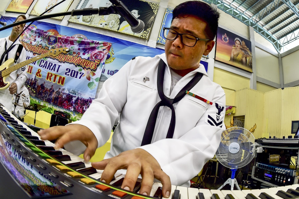 A sailor jams on a keyboard at a band performance.