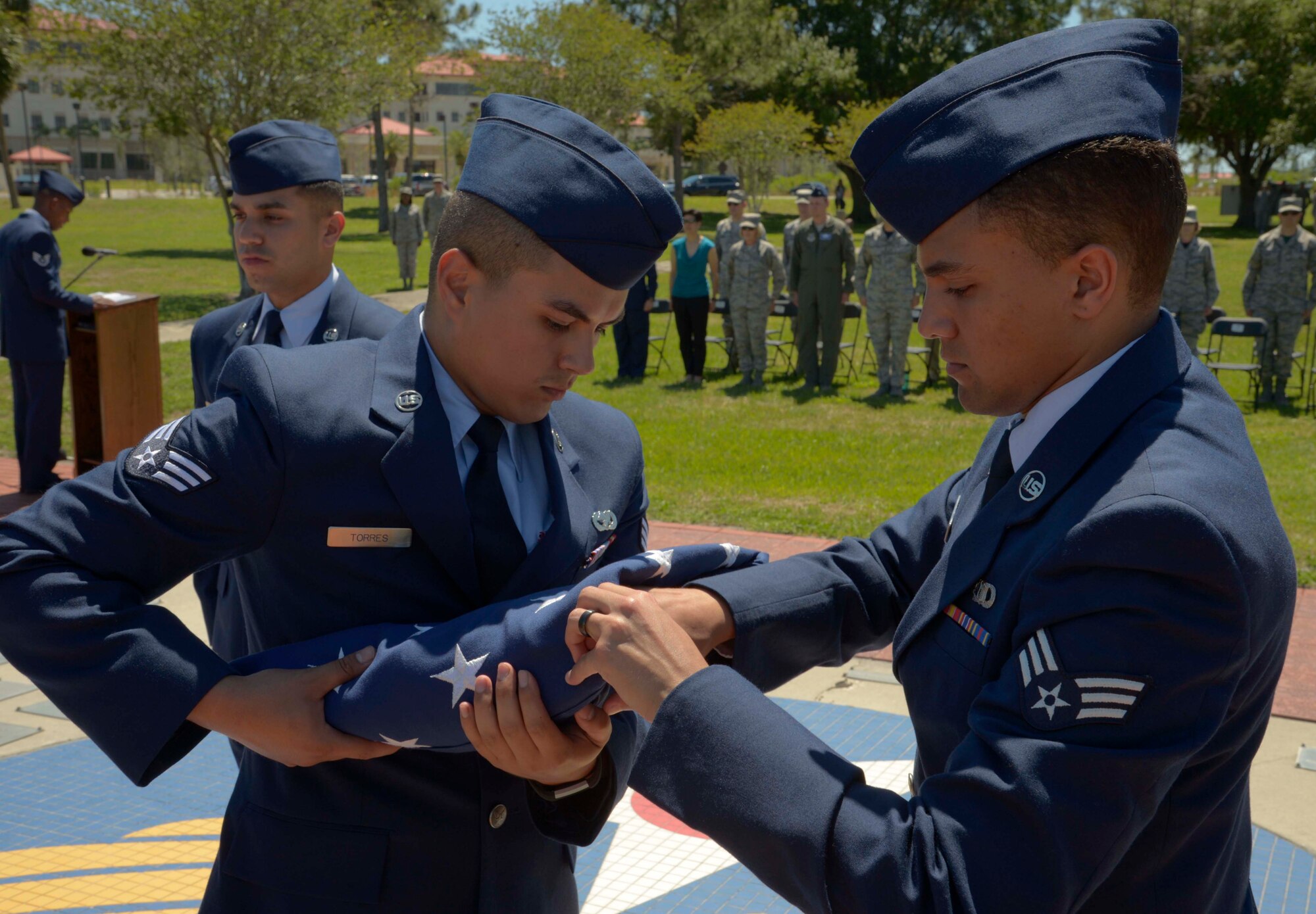 U.S. Air Force Senior Airman Francisco Torres Lopez, left, a vehicle maintenance mechanic assigned to the 6th Logistics Readiness Squadron, and Senior Airman Kevin Beasley, right, an air traffic controller assigned to the 6th Operations Support Squadron, fold an American flag during a Memorial Day ceremony at MacDill Air Force Base, Fla., May 26, 2017. Four Airmen rendered honors to the American flag to pay respect to fallen heroes. (U.S. Air Force photo by Staff Sgt. Vernon L. Fowler Jr.)