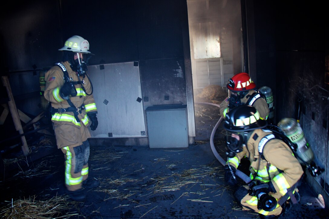 932nd Airlift Wing firefighters trained on intense core special skills particular to their unique jobs on May 21, 2017, at Scott Air Force Base, Illinois.   In preparation, several firefighters lit pallets on fire (in background) to heat up the room, while others began searching for a simulated patient.  These 932nd Civil Engineering Squadron members had already checked the hose system to ensure proper water pressure and availability of the resource in case it was needed to help put out a fire.  Approximately 32 members of the 932nd Civil Engineering Squadron suited up with oxygen tanks to take their turns and get the hot, dark, challenging experience. (U.S. Air Force photo by Lt. Col. Stan Paregien)