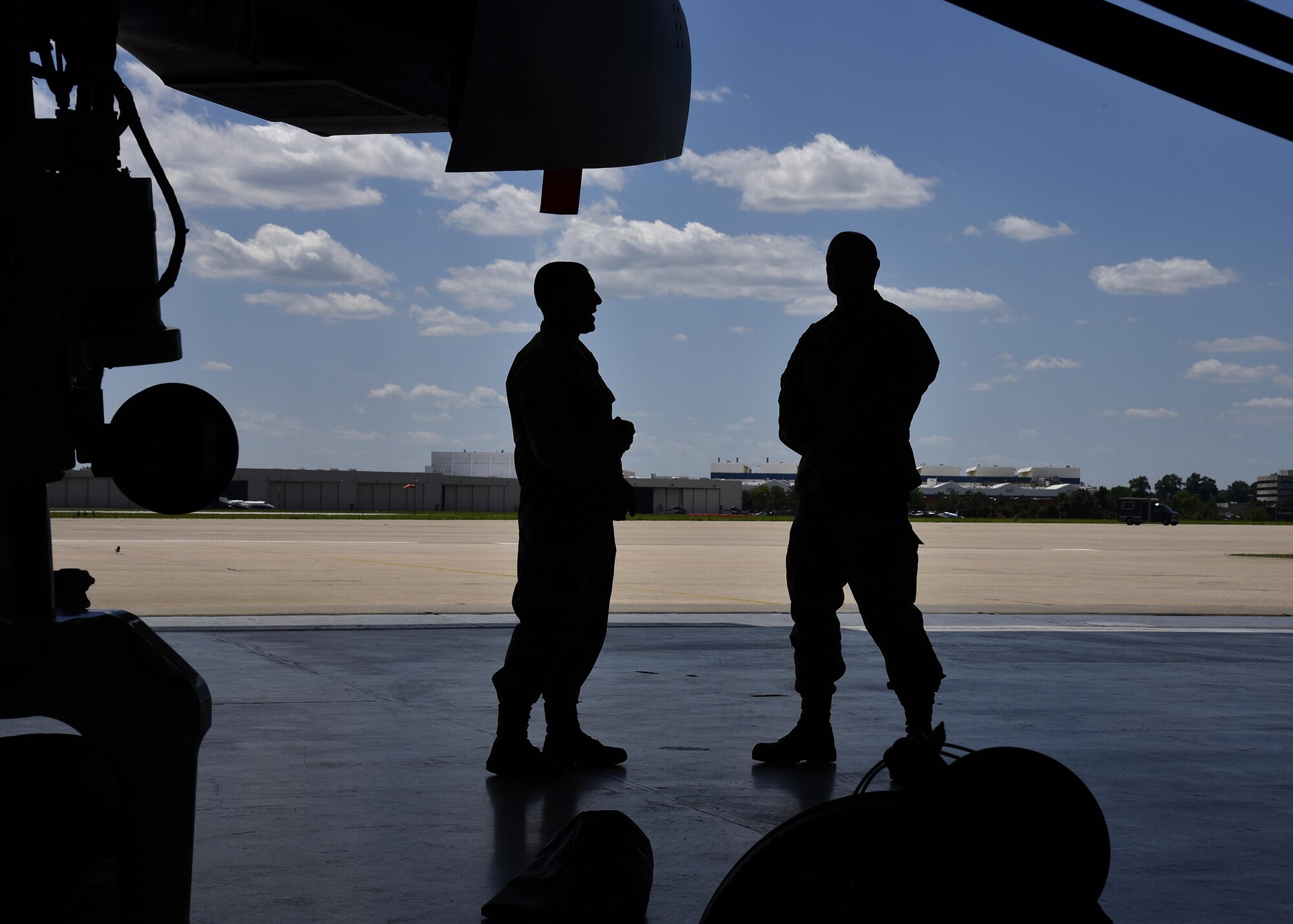Two service members talk to each other June 1, 2017, in the fuel cell hangar at Warfield Air National Guard Base, Md. They were participating in a base tour being conducted for visiting members of the Office of Cost Assessment and Program Evaluation. (U.S. Air National Guard photo by Airman Sarah M. McClanahan /Released Master Sgt. Chris Schepers)