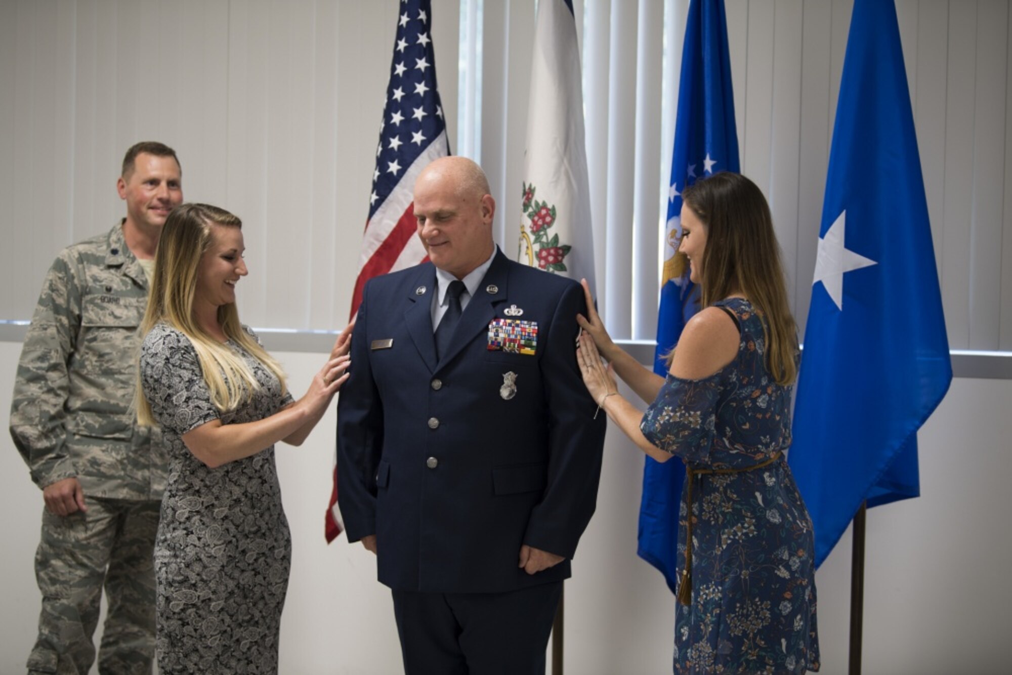 Chief Master Sgt. P. Wayne Hughes stands as his daughters affix his new rank onto his uniform June 3, 2017 during a promotion ceremony held in his honor at McLaughlin Air National Guard Base, Charleston, W.Va. Hughes is a 27-year veteran of Security Forces who will assume the role of chief enlisted manager with this promotion. (U.S. Air National Guard photo by Capt. Holli Nelson) 