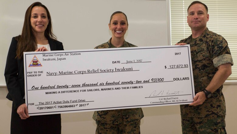 Melissa Hornbrook, director of the Navy-Marine Corps Relief Society (NMCRS), left, U.S. Marine Corps 1st Lt. Melissa Heisterberg, deputy director of the public affairs office with Headquarters and Headquarters Squadron and active-duty fund drive (ADFD)  coordinator, center, and Sgt. Maj. Christopher J. Garza, sergeant major of Marine Corps Air Station Iwakuni, hold a large check of money raised for NMCRS during an awards ceremony for the ADFD in support of the NMCRS at MCAS Iwakuni, Japan, June 1, 2017. The ceremony acknowledged Marines and Sailors for their contribution to the NMCRS ADFD. The NMCRS is a non-profit organization that runs solely on donations. It gives financial, educational and other need-based assistance to active-duty and retired Sailors and Marines and their families. MCAS Iwakuni is the Marine Corps installation that raised the most money for NMCRS for the year. (U.S. Marine Corps photo by Lance Cpl. Gabriela Garcia-Herrera)