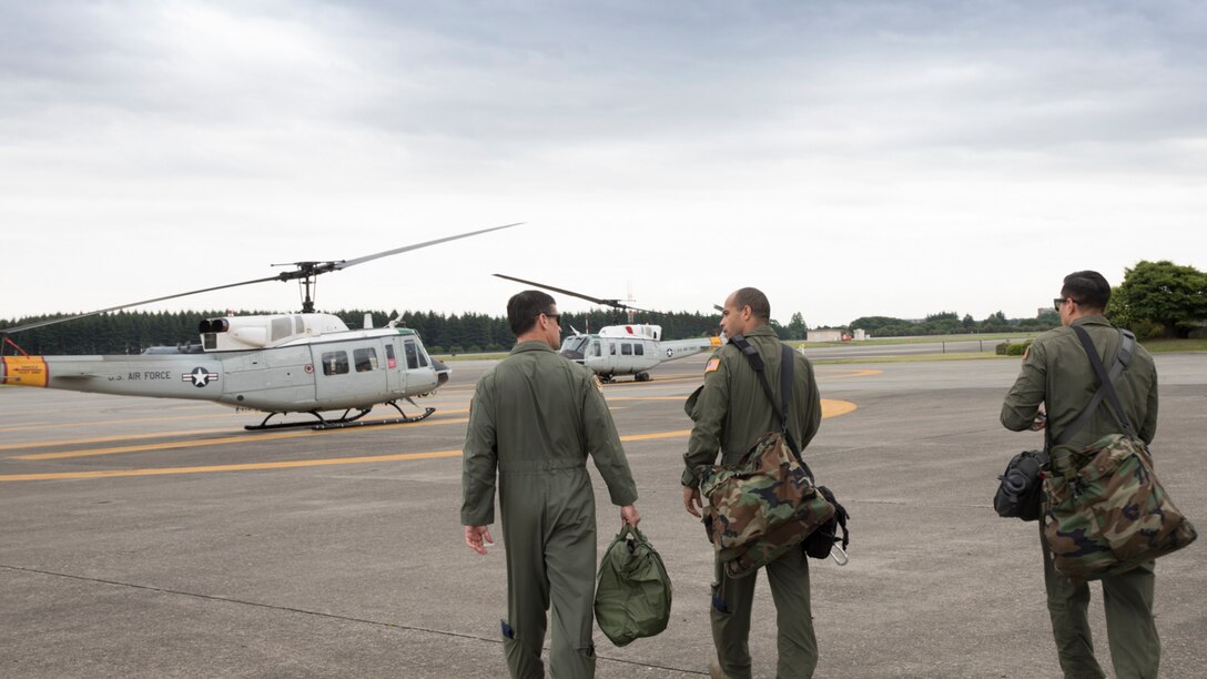 (Left to right) Col. Robert Dotson, 374th Operations Group commander, Capt. Brandon Jones, 374th Airlift Wing UH-1N pilot, and Tech. Sgt. Michael Wright, 459th Airlift Squadron UH-1N special mission aviator evaluator, walk onto the flightline at Yokota Air Base, Japan, May 25, 2017. Dotson made his final flights in a C-12 Huron and an UH-1N Iroquois during that day. (U.S. Air Force photo by Yasuo Osakabe)