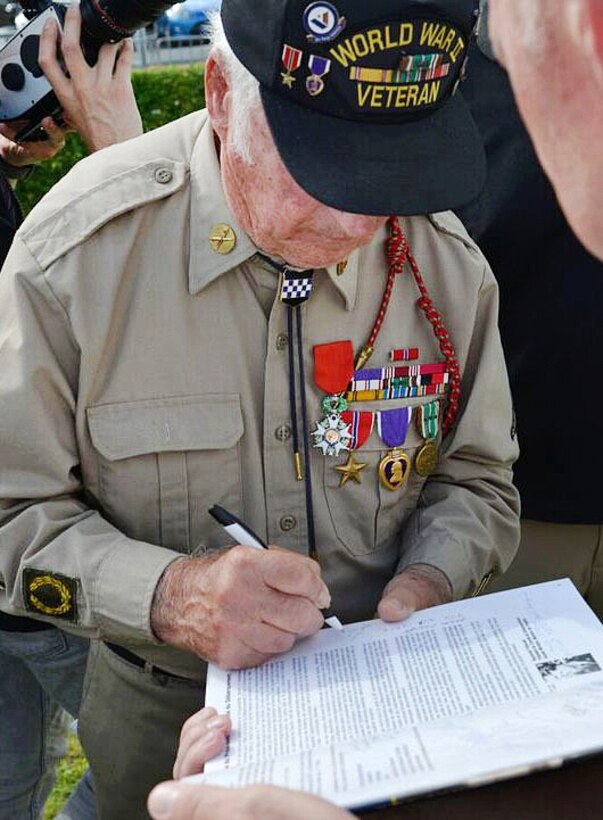 Alfred Bucci, a D-Day veteran, signs a book for a fan during a ceremony in Carentan, France, June 2, 2017. Air Force photo by Airman 1st Class Alexis C. Schultz  