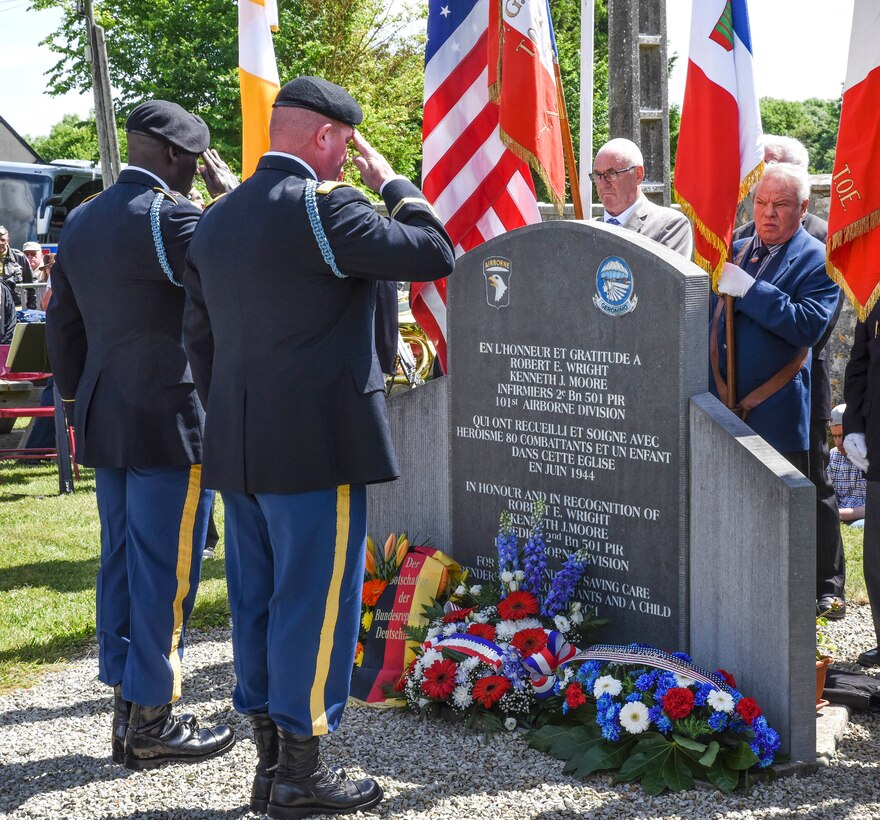 Army Col. Al Boyer, right, commander of the 101st Airborne Division’s 1st Brigade Combat Team, and Command Sgt. Maj. James Manning render honors to a memorial dedicated to Kenneth Moore and Robert Wright in Angoville-au-Plain, France, June 3, 2017. As medics, Moore and Wright provided medical care to 80 combatants, both allies and enemies, and one child at the Angoville-au-Plain church in June 1944. Army photo by Staff Sgt. Tamika Dillard
