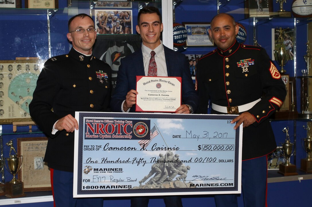 Bishop O’ Connell High School senior, Cameron Cairnie, middle, receives a $150,000 Naval Reserve Officers Training Corps Marine Option Scholarship during a senior awards ceremony in Arlington, Virginia, May 31, 2017. U.S. Marine Corps Capt. Michael Bell, left, executive officer of Marine Corps Recruiting Station Frederick, and Staff Sgt. Jhosue Escate, recruiter for Marine Corps Recruiting Sub-station Alexandria, RS Frederick, presented the scholarship to the Alexandria, Virginia, native, which will cover the cost of tuition, books, and a small living stipend. (U.S. Marine Corps photo by Staff Sgt. Anthony Kirby/Released)