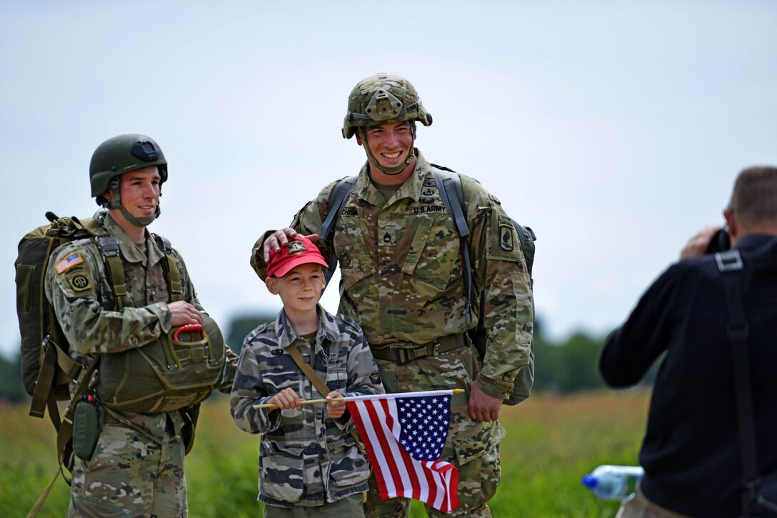 Army paratroopers pose for a photograph with a child after participating in an airborne operation to commemorate D-Day in Sainte-Mere-Eglise, France, June 4, 2017. Air Force photo by Airman 1st Class Alexis C. Schultz